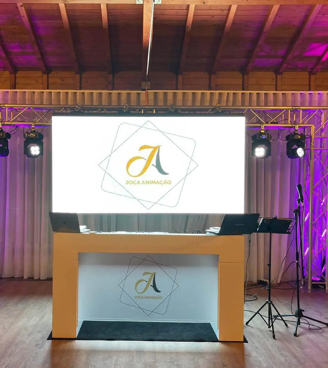 Bancada de DJ com painel LED e iluminação profissional, representando o serviço de aluguer de material e equipamentos da Joca Animação.