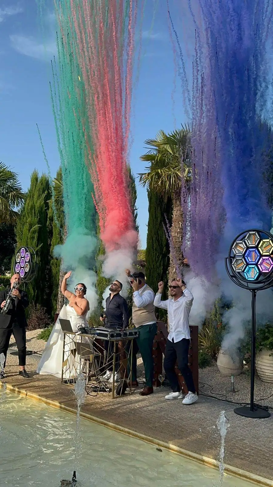 Momento do Pack Pro Sunset da Joca Animação, com DJ, noivos e fumos coloridos a criar um ambiente festivo durante o casamento ao ar livre.
