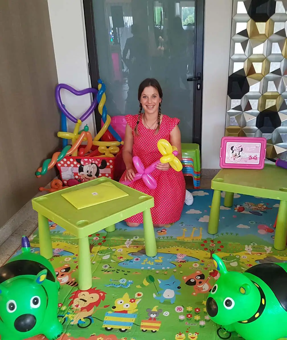 Animadora infantil a criar figuras com balões numa zona de atividades para crianças.