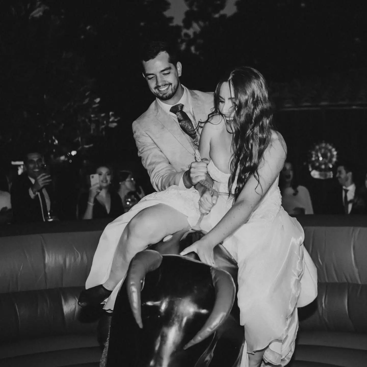 Casal a divertir-se no touro mecânico da Joca Animação durante a festa, criando um momento hilariante e inesquecível para os convidados.